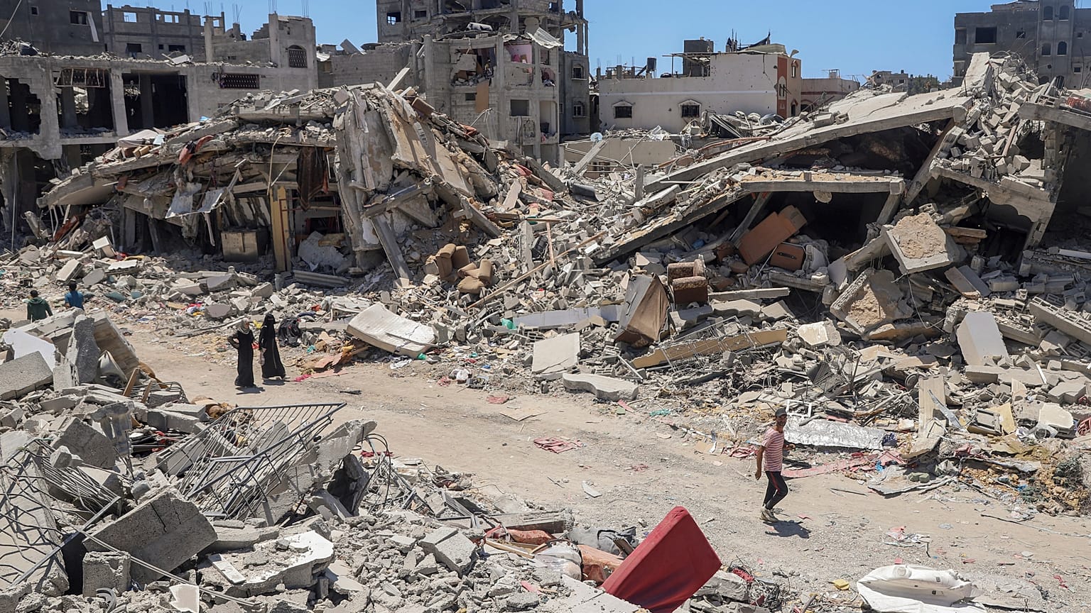 فلسطينيون يسيرون في الدمار الذي خلفه الهجوم الجوي والبري الإسرائيلي في جباليا شمال قطاع غزة في 30 مايو/أيار 2024