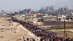 فلسطينيون ينتظرون عبور شاحنات المساعدات في وسط قطاع غزة في 19 مايو 2024. 