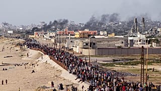 فلسطينيون ينتظرون عبور شاحنات المساعدات في وسط قطاع غزة في 19 مايو 2024. 