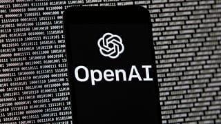  Le logo de l'OpenAI apparaît sur un téléphone portable devant un écran d'ordinateur contenant des données binaires aléatoires, le 9 mars 2023, à Boston.