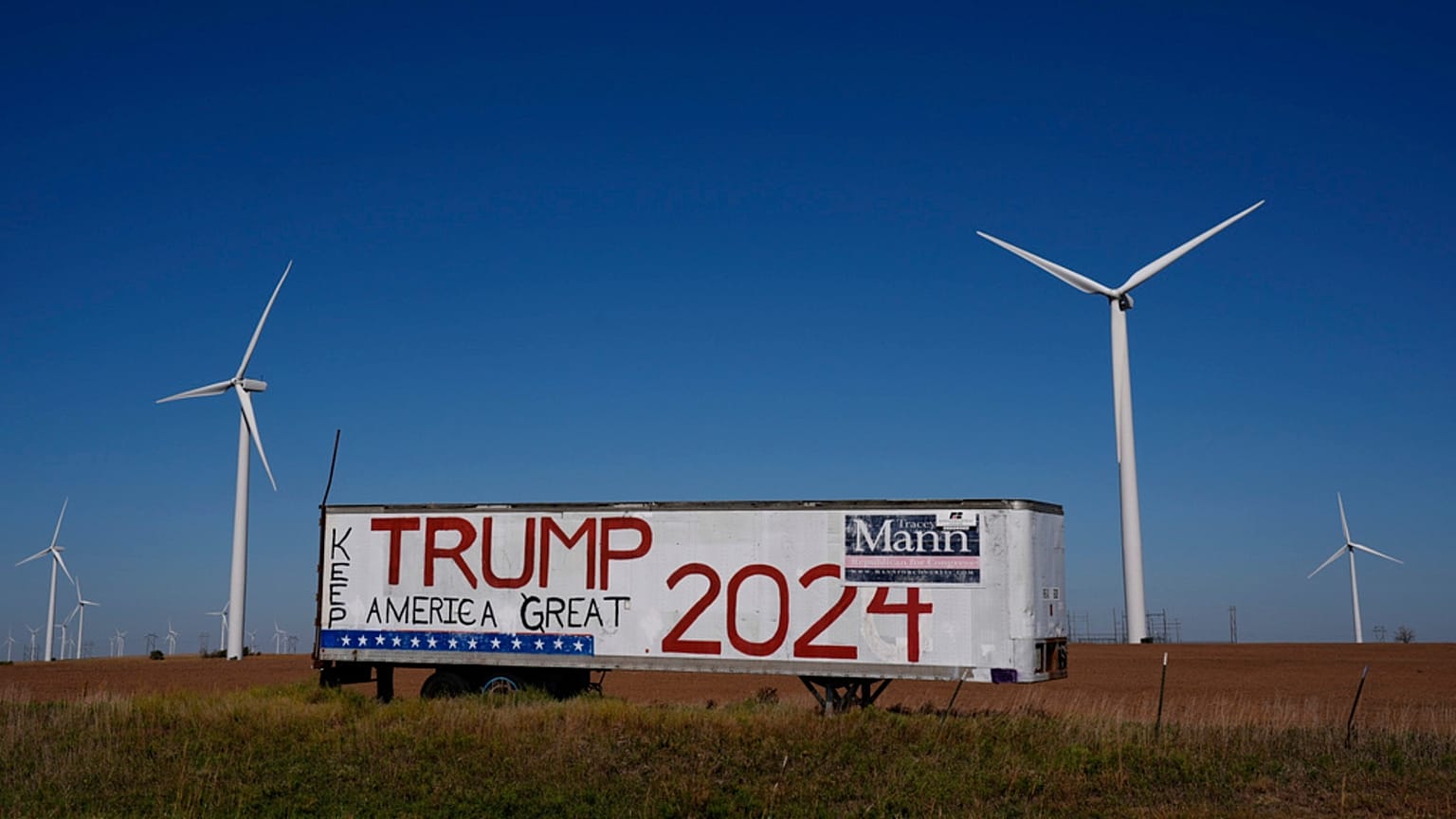 A trailer with a sign supporting Republican presidential nominee former President Donald Trump stands adjacent to a wind farm. 