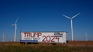 A trailer with a sign supporting Republican presidential nominee former President Donald Trump stands adjacent to a wind farm.