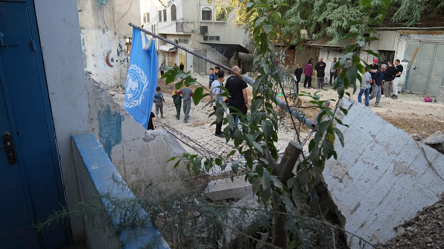 فلسطينيون يمرون بالقرب من أنقاض مكتب الأمم المتحدة لمساعدة اللاجئين الفلسطينيين الذي تم هدمه جزئياً خلال عملية الجيش الإسرائيلي في طولكرم، 31 أكتوبر/تشرين الأول 2024