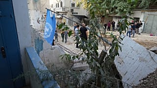 فلسطينيون يمرون بالقرب من أنقاض مكتب الأمم المتحدة لمساعدة اللاجئين الفلسطينيين الذي تم هدمه جزئياً خلال عملية الجيش الإسرائيلي في طولكرم، 31 أكتوبر/تشرين الأول 2024