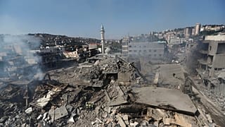 Hizbullah kurtarma görevlileri, ortada altta, Lübnan'ın güneyindeki Nabatiye kasabasında Cumartesi gecesi İsrail hava saldırıları sonucu yıkılan binaların enkazı üzerinde duruyorlar.