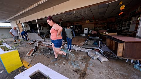 Library picture of an assistant shop manager walking through debris of the damaged shop in the aftermath of Hurricane Helene