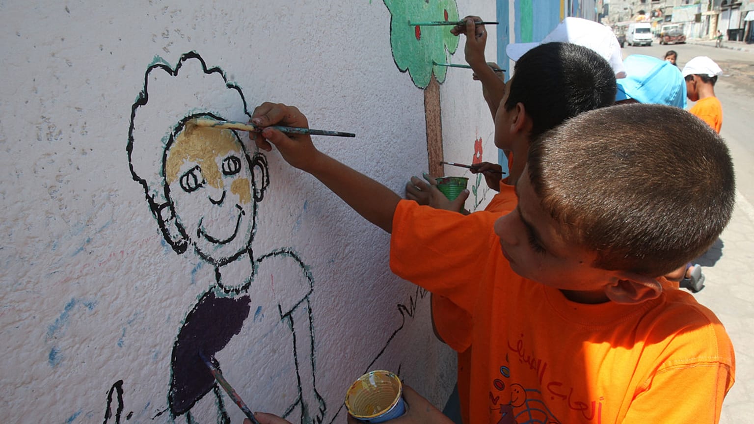 الأطفال الفلسطينيون يرسمون على جدار مدرسة تديرها وكالة الأمم المتحدة لإغاثة وتشغيل اللاجئين.