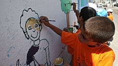 الأطفال الفلسطينيون يرسمون على جدار مدرسة تديرها وكالة الأمم المتحدة لإغاثة وتشغيل اللاجئين.