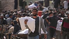 فلسطينيون يتجمعون لاستلام أكياس الطحين التي وزعتها الأونروا، وكالة الأمم المتحدة لمساعدة اللاجئين الفلسطينيين، في دير البلح، وسط قطاع غزة، السبت، 2 نوفمبر، 2024. 