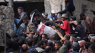 فلسطينيون يتجمعون لاستلام أكياس الطحين التي وزعتها الأونروا، في دير البلح، وسط قطاع غزة، السبت، 2 نوفمبر، 2024. 