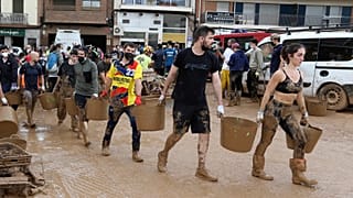 Una cadena humana de vecinos y voluntarios ayuda a extraer barro de las zonas afectadas.