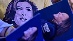 Apoiantes carregam cartazes da campanha de Kamala Harris num comício.