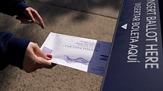 Una mujer depositando su voto por correo