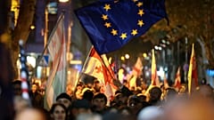 Manifestantes com bandeiras da Geórgia e da UE, em cima, participam numa manifestação contra alegadas violações nas recentes eleições parlamentares em Tbilisi, Geórgia, 4 de novembro de 2024.