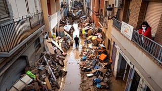 Emberek sétálnak egy utcán, amelynek szélén bútorokat és szemetet halmoztak fel egy árvíz sújtotta területen a spanyolországi Valencia tartományban, Paiporta településen 2024. november 5-én, kedden. 