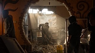 Bir Filistinli, İsrail'in Refah'a yönelik saldırısında komşusunun hasar gören evine bakıyor