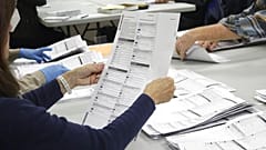 An election worker examines a ballot at the Clackamas County Elections office