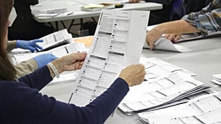 An election worker examines a ballot at the Clackamas County Elections office