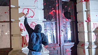 Novi Sad'da bir tren istasyonunun çatısının çökmesi üzerine ölen kişiler için düzenlenen gösteride bir protestocu belediye binasına grafiti çizdi, 5 Kasım 2024