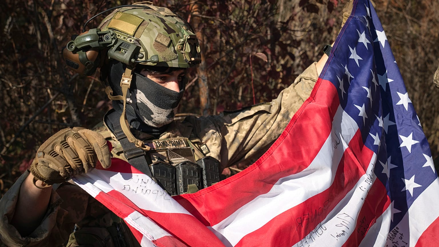 Um combatente voluntário do estado norte-americano do Texas, que serve no 23.º batalhão de espingardas das forças armadas da Ucrânia, segura uma bandeira dos EUA na região de Kharkiv, a 26 de outubro de 2024.