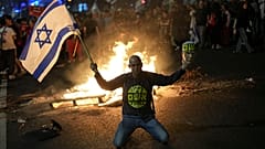 Διαδηλωτής κρατάει ισραηλινή σημαία κατά τη διάρκεια διαμαρτυρίας για την αιφνιδιαστική αποπομπή του υπουργού Άμυνας Γιοάβ Γκαλάντ, Τελ Αβίβ, Ισραήλ, 05.11.2024.