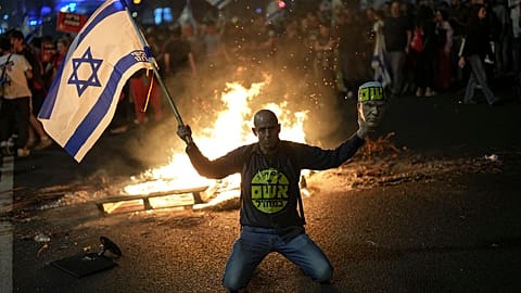 Savunma Bakanı Yoav Gallant'ın sürpriz bir şekilde görevden alınmasına tepki olarak düzenlenen protesto sırasında bir gösterici İsrail bayrağı tutuyor, Tel Aviv, İsrail, 05.11.2024.