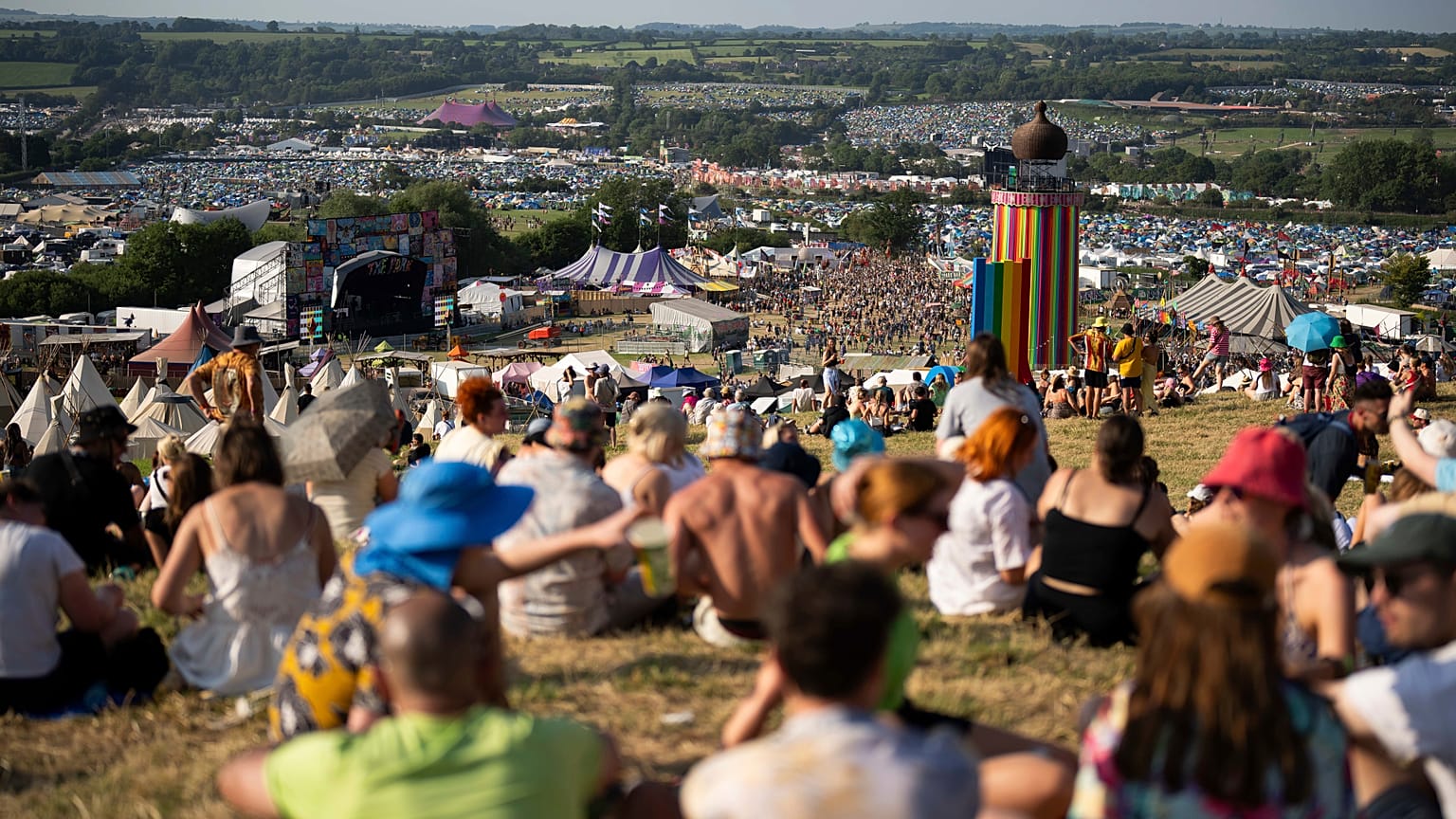 Festival goers sit on a hill at the Glastonbury Festival in Worthy Farm, Somerset, England, Wednesday, June 26, 2024