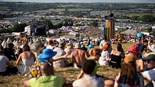 Festival goers sit on a hill at the Glastonbury Festival in Worthy Farm, Somerset, England, Wednesday, June 26, 2024