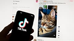 A TikTok logója egy mobiltelefonon, háttérben egy számítógép képernyőjével Bostonban 2023.03.18-án.