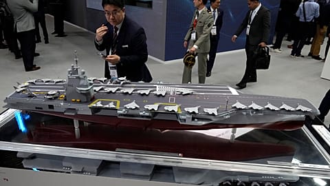 A visitor watches a replica of the the French new generation aircraft carrier during the Euronaval weapons show, Monday, Nov. 4, 2024 in Paris. 
