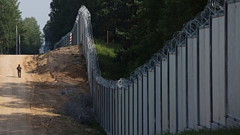 Польский пограничник патрулирует район недавно построенной стальной стены на границе между Польшей и Беларусью, июнь 2022 года.
