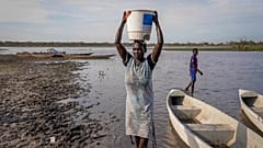 امرأة تحمل الماء على رأسها من أحد المستنقعات في مقاطعة كانال بيجي في جنوب السودان يوم الخميس 4 مايو/أيار 2023