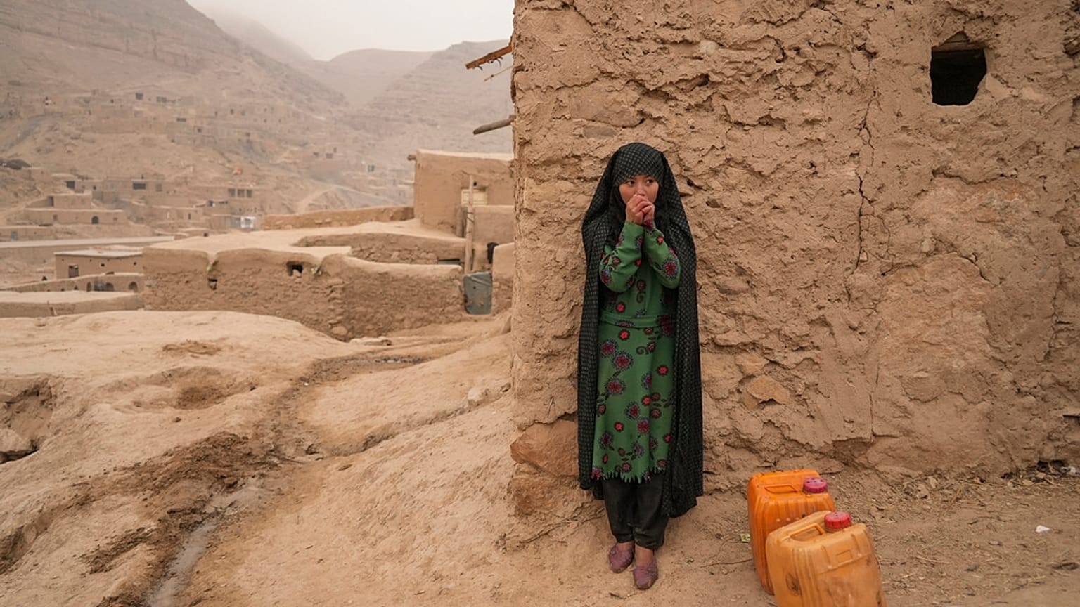 DOSSIER - Une jeune fille afghane se réchauffe les mains alors qu'elle se repose après avoir porté de l'eau à Balucha, en Afghanistan, le lundi 14 décembre 2021. (AP Photo/Mstyslav Chernov, File)