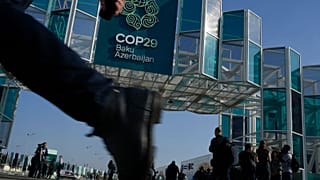 Varias personas caminan frente a la sede de la cumbre climática de la ONU COP29, el 10 de noviembre de 2024, en Bakú, Azerbaiyán.