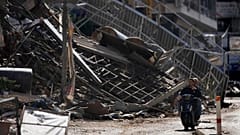 İki adam, 11 Kasım 2024 Pazartesi günü Lübnan'ın başkenti Beyrut'un güney banliyösü Dahiye'de İsrail hava saldırısı sonucu yıkılan bir binanın önünden scooter ile geçiyor. 