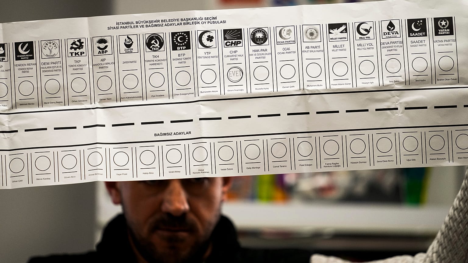 Bu fotoğrafta Türkiye'deki yerel seçimlerde bir sandık görevlisinin oy pusulasını tuttuğu görülüyor, 31 Mart 2024