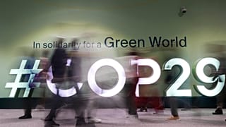 أشخاص يسيرون في قمة الأمم المتحدة للمناخ COP29، الأربعاء، 13 نوفمبر/تشرين الثاني 2024، في باكو، أذربيجان