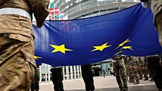 I militari tengono la bandiera dell'Unione Europea mentre partecipano alla cerimonia dell'alzabandiera