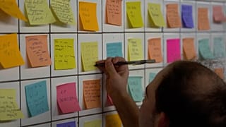 Man putting sticky note on the wall of subway tunnel as part of 'Subway Therapy.'