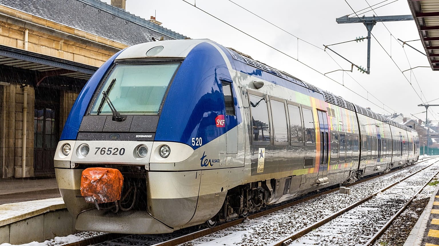 An SNCF TER train stands at a snowy station