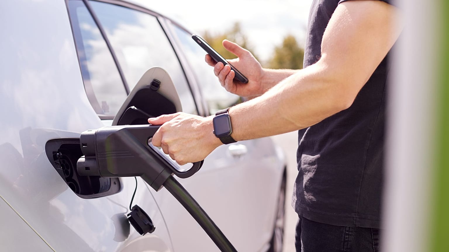 Un hombre recargando su coche eléctrico en una electrolinera.