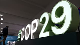 An attendee walks near a sign for the COP29 U.N. Climate Summit, Saturday, Nov. 9, 2024, in Baku, Azerbaijan.