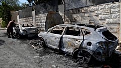 فلسطيني يتفحص سيارة محترقة شوهدت صباح يوم الجمعة 16 أغسطس/آب 2024، بعد هجوم شنه مستوطنون إسرائيليون في قرية جيت بالضفة الغربية