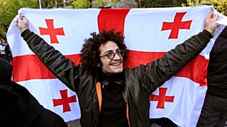 Ein Demonstrant hält eine georgische Flagge während einer Kundgebung gegen angebliche Unregelmäßigkeiten bei den jüngsten Parlamentswahlen in Tiflis, Georgien, Dienstag, 5. November 2024