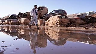 Egy férfi sétál a felhalmozott autók mellett a több száz halottat vagy eltűntet követelő árvíz után a spanyolországi Valencia régióban, Catarrojában, 2024. november 12-én, kedden.