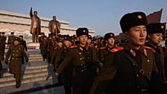 Észak-koreai katonák a két Kim-előd szobra előtt