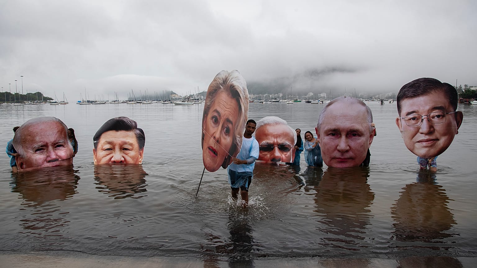 Egy brazil őslakos mozgalom aktivistái a G20-csúcson részt vevő vezetők gigantikus méretű arcképeit tartják maguk előtt