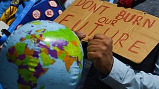 متظاهر يحمل لافتة كتب عليها "لا تحرقوا مستقبلنا" خلال قمة المناخ COP29 التابعة للأمم المتحدة، يوم الاثنين، 18 نوفمبر 2024، في باكو، أذربيجان.