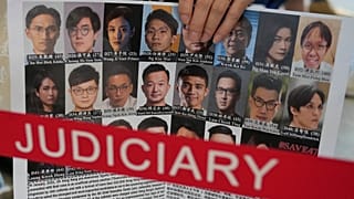 FILE - A supporter holds a placard with the photos of some of the 47 pro-democracy defendants outside a court in Hong Kong, on July 8, 2021.