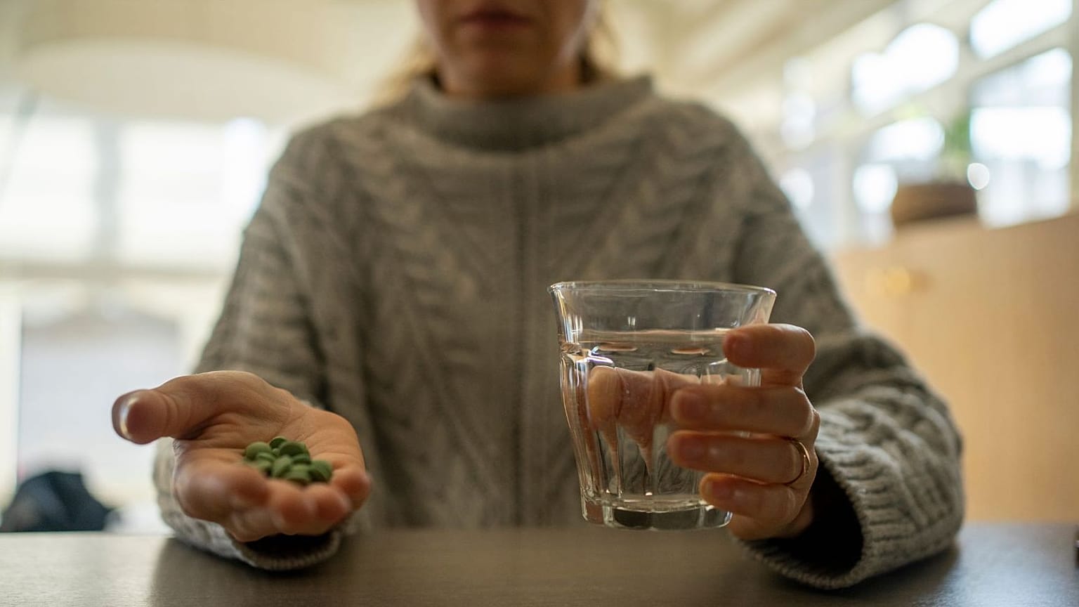 Una mujer prepara una serie de pastillas para tomarse. 